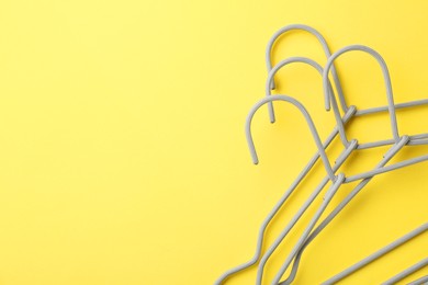 Hangers on yellow background, top view. Space for text