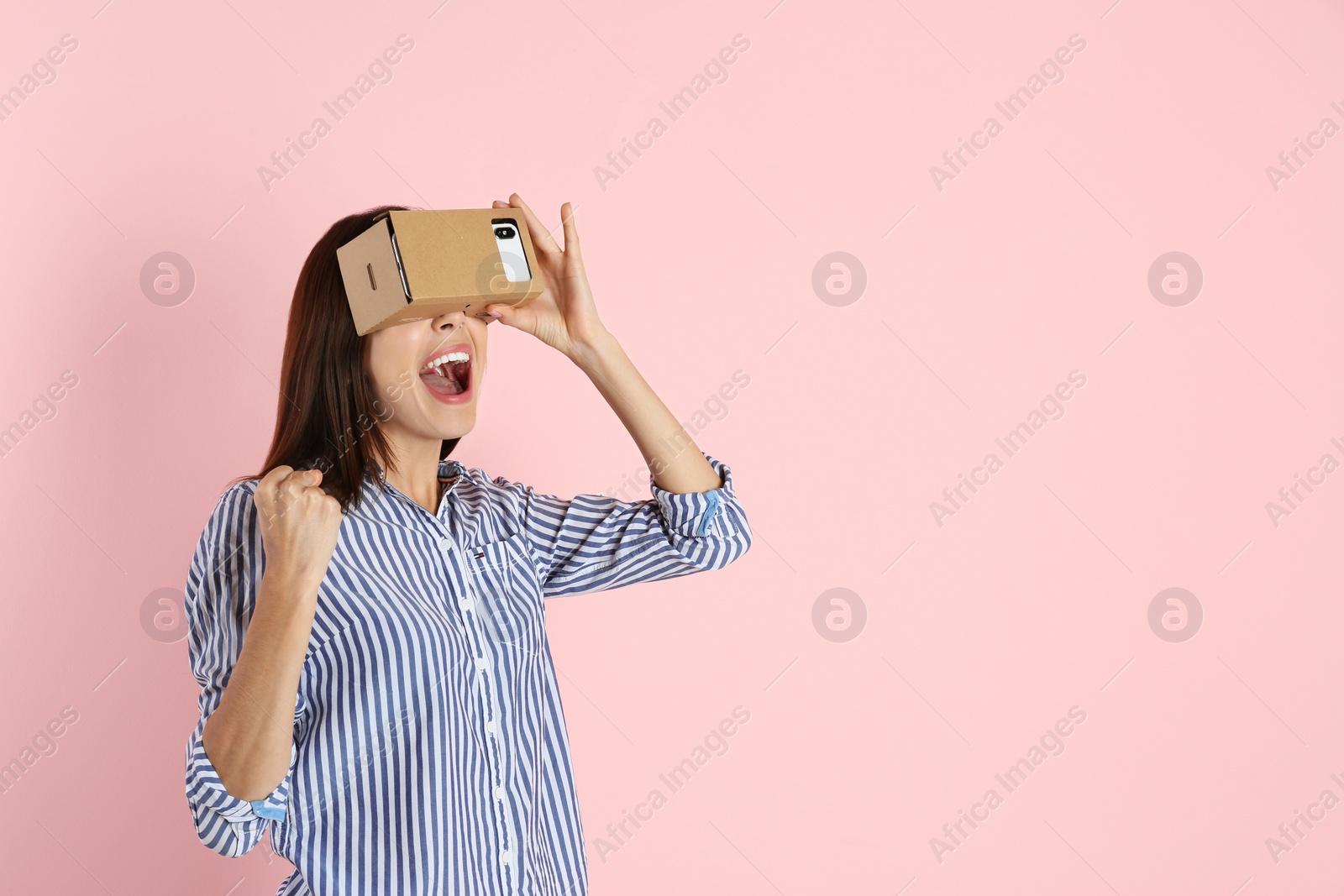 Photo of Young woman using cardboard virtual reality headset on color background. Space for text