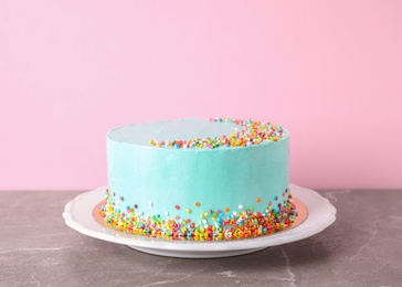 Plate with fresh delicious birthday cake on table against color background