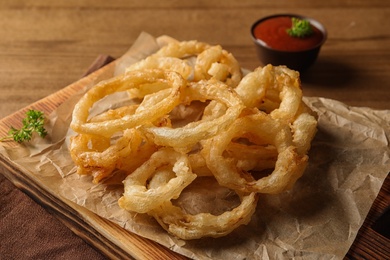 Photo of Homemade delicious golden breaded and deep fried crispy onion rings on wooden background, closeup