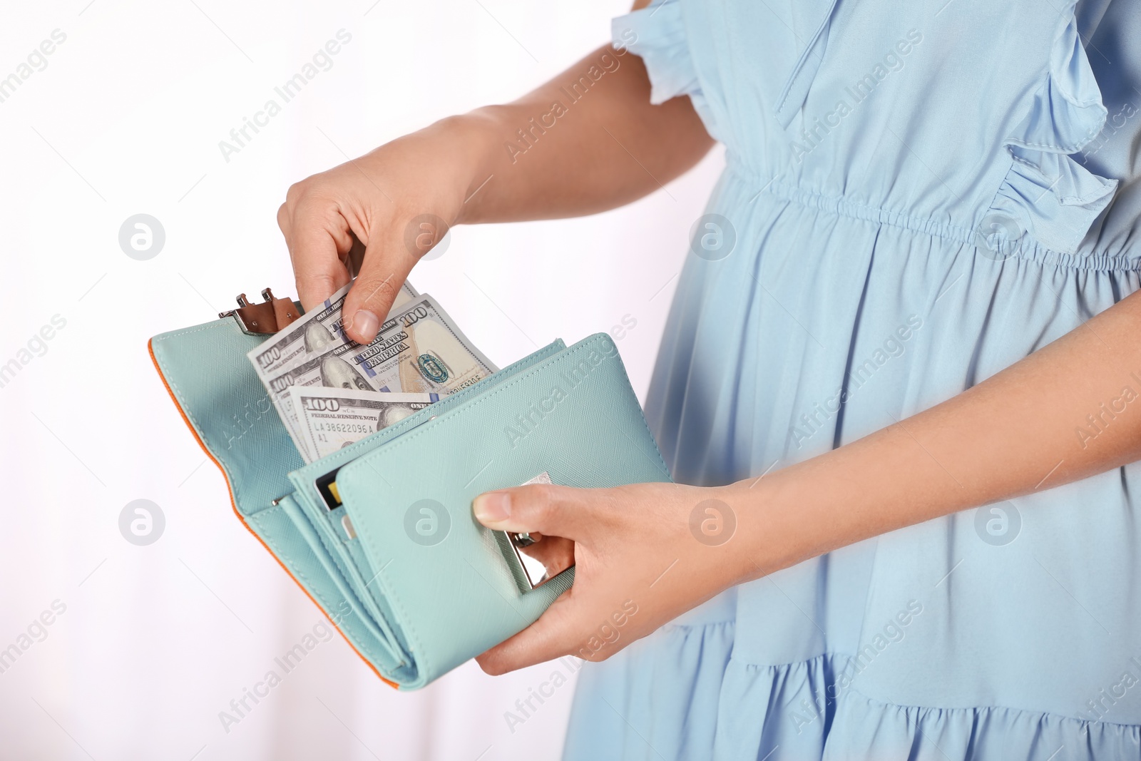 Photo of Woman taking out cash from stylish wallet on light background, closeup