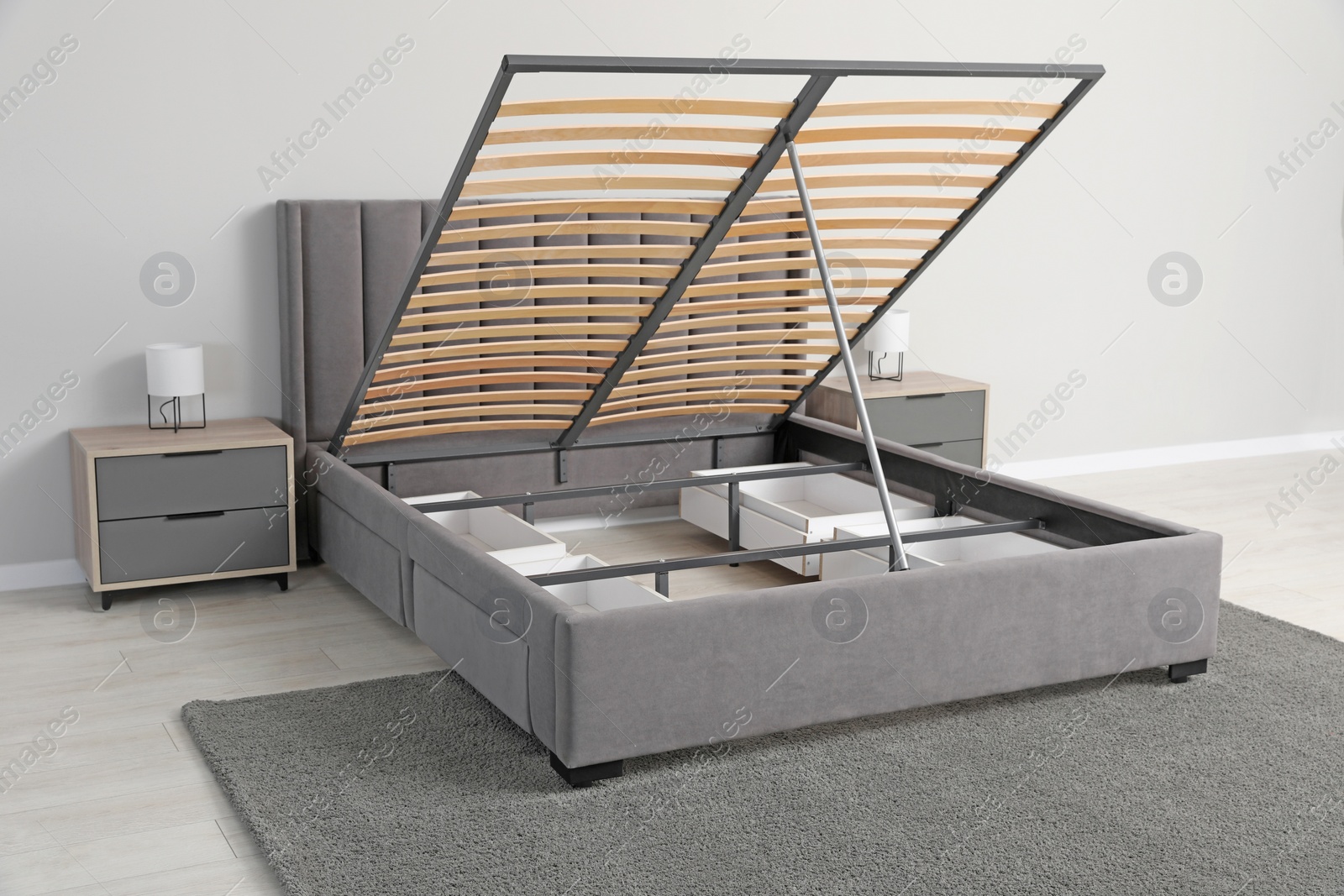 Photo of Comfortable bed with storage space for bedding under lifted slatted base in room