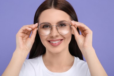 Photo of Portrait of smiling woman in stylish eyeglasses on violet background