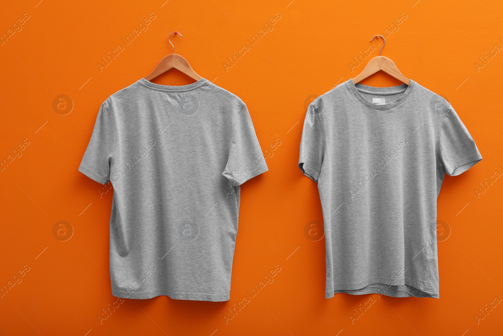 Photo of Hangers with blank t-shirts on color background. Mockup for design