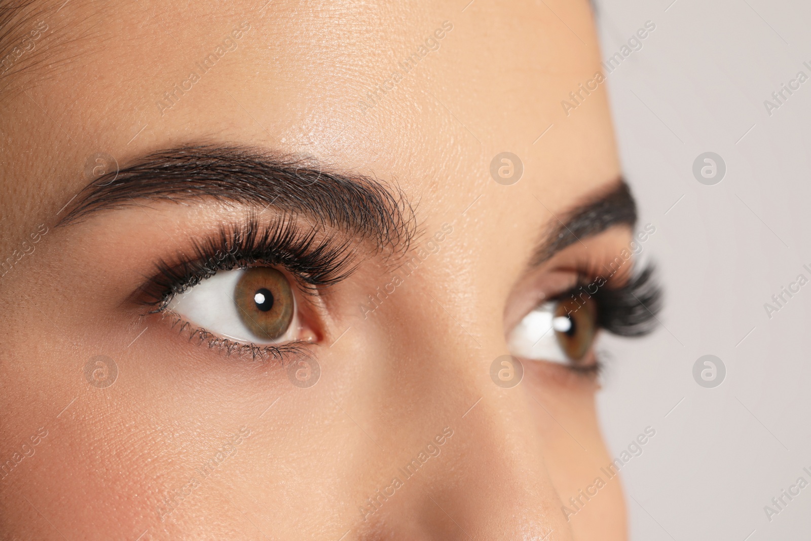 Photo of Beautiful young woman with long eyelashes on light background, closeup