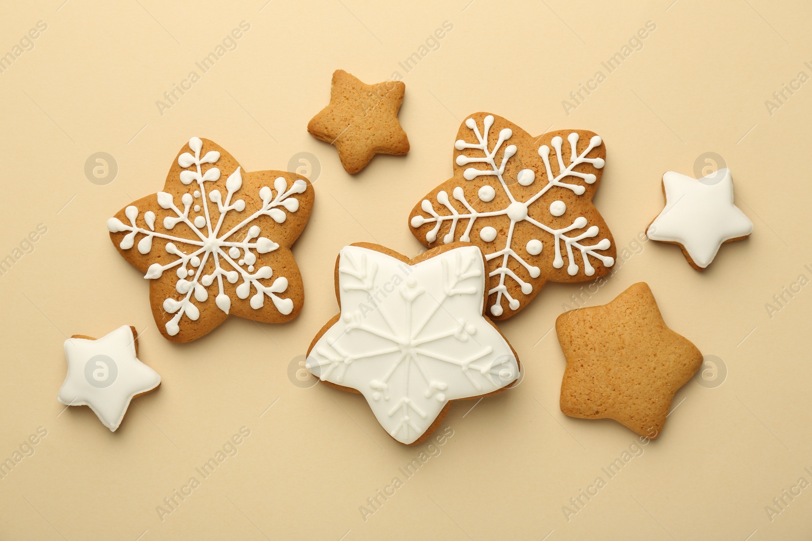 Photo of Tasty Christmas cookies with icing on beige background, flat lay