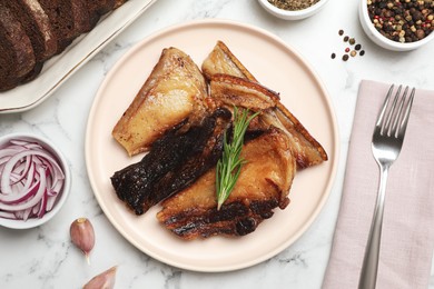 Photo of Tasty fried pork lard with rosemary on white marble table, flat lay