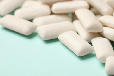 Photo of Many chewing gum pieces on turquoise background, closeup