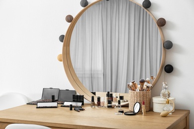 Photo of Cosmetics and brushes on dressing table in makeup room