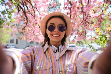 Happy young woman taking selfie in park