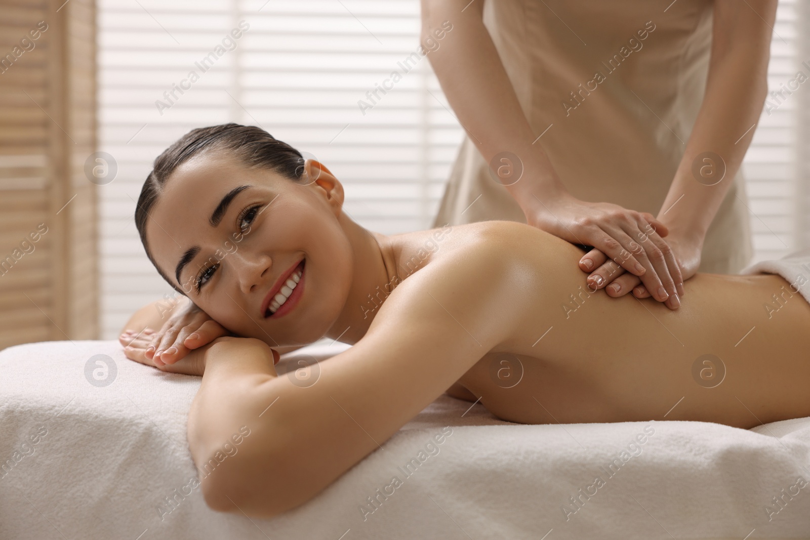 Photo of Woman receiving back massage on couch in spa salon