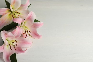 Photo of Beautiful pink lily flowers on white wooden table, above view. Space for text