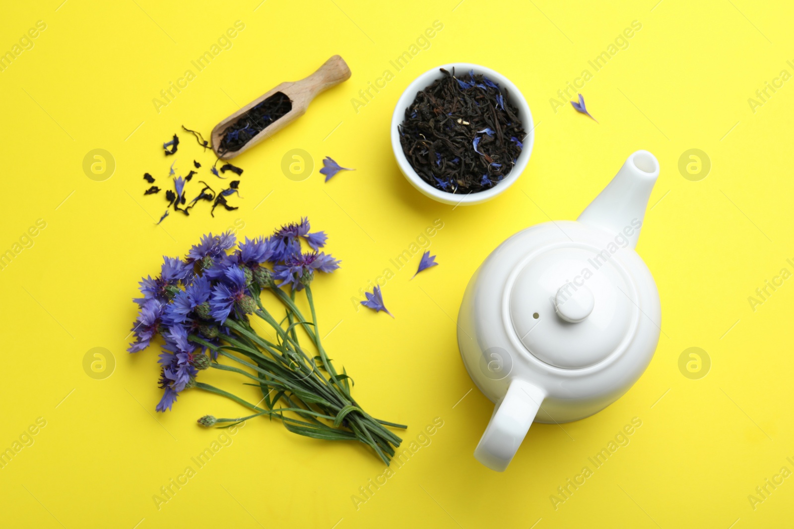 Photo of Flat lay composition with dry tea leaves and cornflowers on yellow background