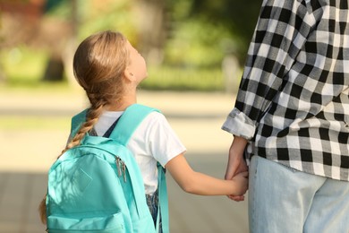 Little girl with her mother on way to school, back view