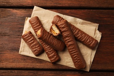 Photo of Sweet tasty chocolate bars with caramel on wooden table, top view