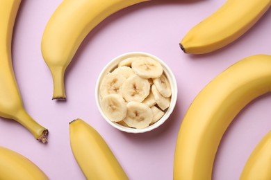 Photo of Bowl with cut bananas and whole fruits on pink background, flat lay