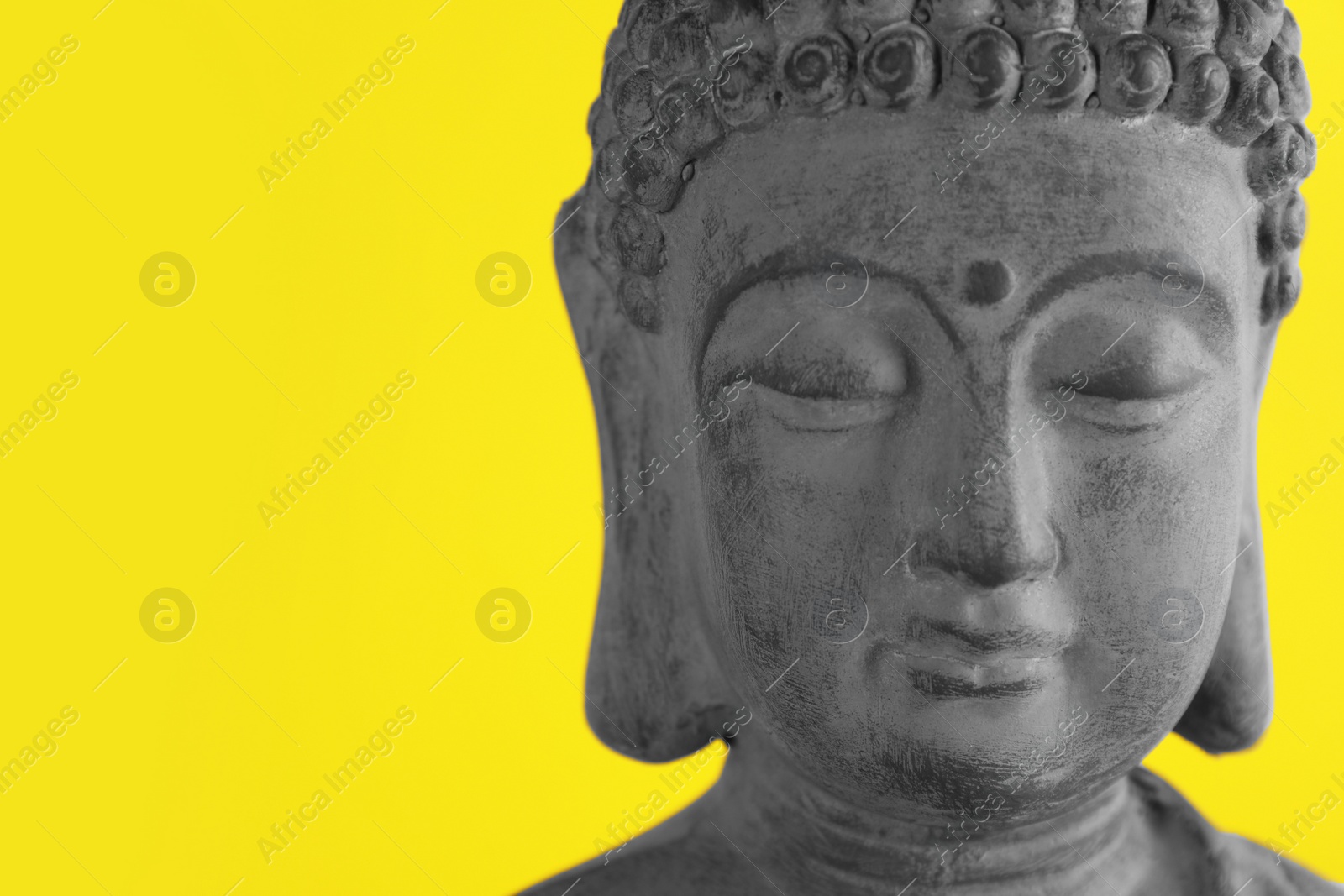 Photo of Beautiful stone Buddha sculpture on yellow background, closeup. Space for text