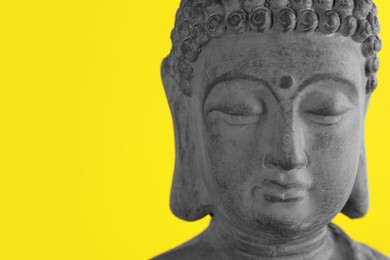 Beautiful stone Buddha sculpture on yellow background, closeup. Space for text
