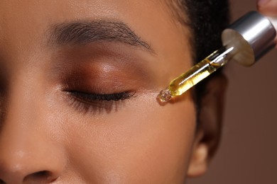 Photo of Woman applying serum onto her face, closeup
