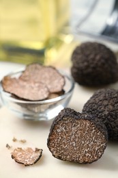 Whole and cut black truffles on table, closeup