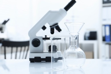 Photo of Laboratory analysis. Different glassware and microscope on white table indoors