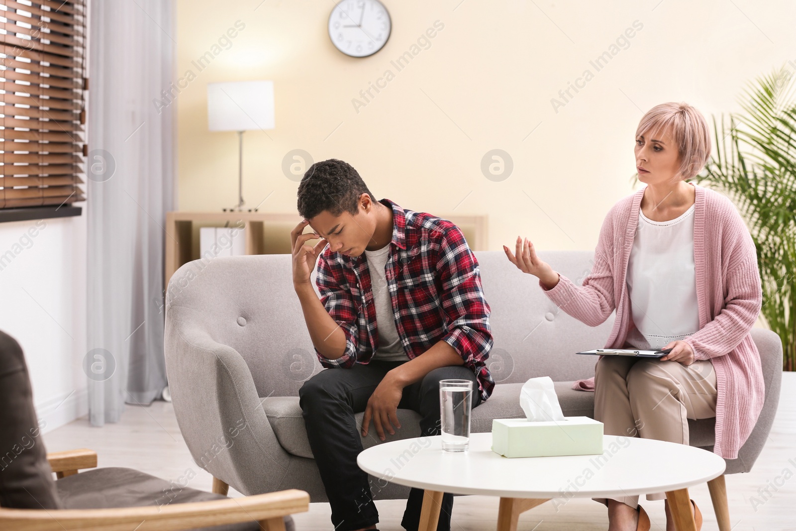 Photo of Psychotherapist working with teenage African-American boy in office