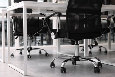 Photo of Comfortable office chairs and tables in meeting room, closeup