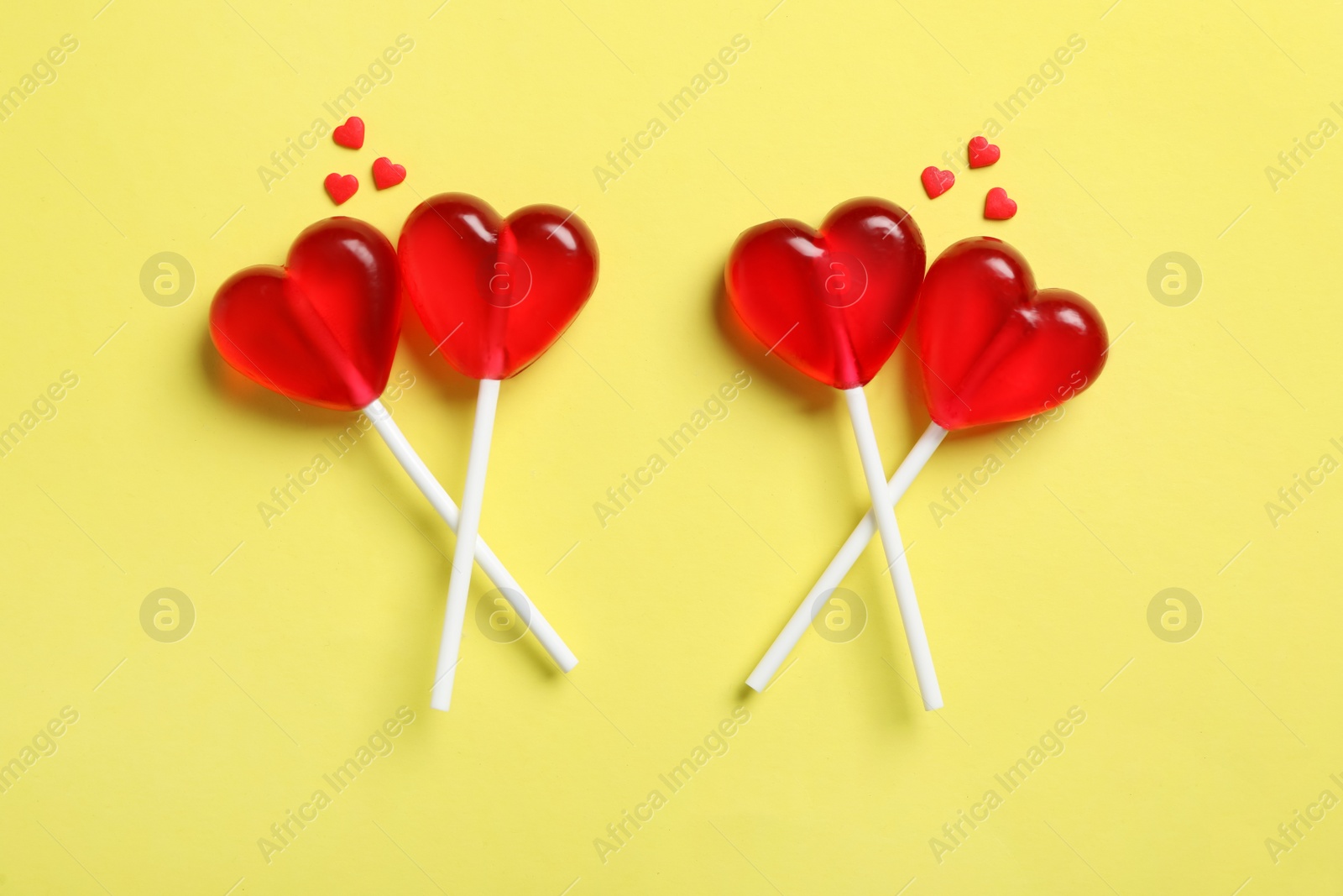 Photo of Sweet heart shaped lollipops and sprinkles on yellow background, flat lay. Valentine's day celebration