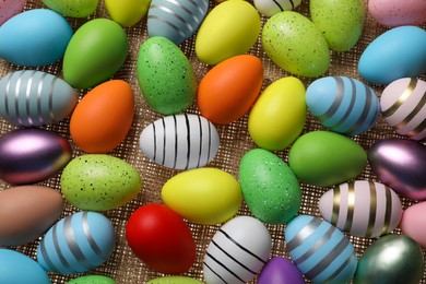 Photo of Many painted Easter eggs on burlap, flat lay