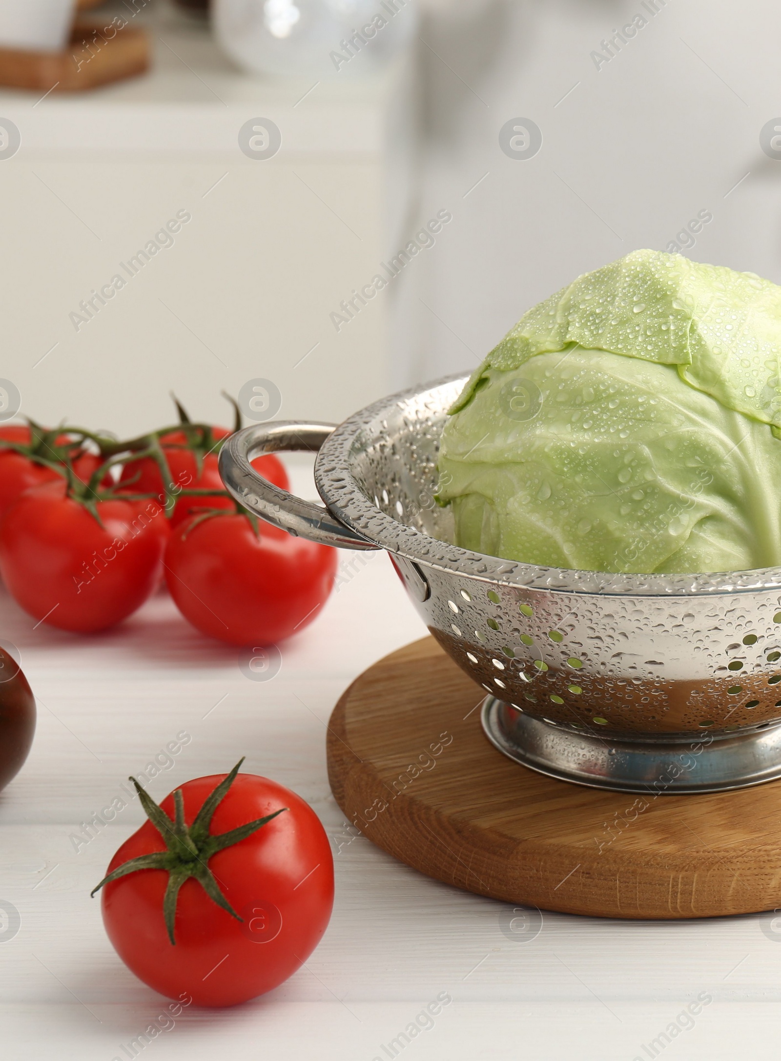 Photo of Wet cabbage in colander on white wooden table