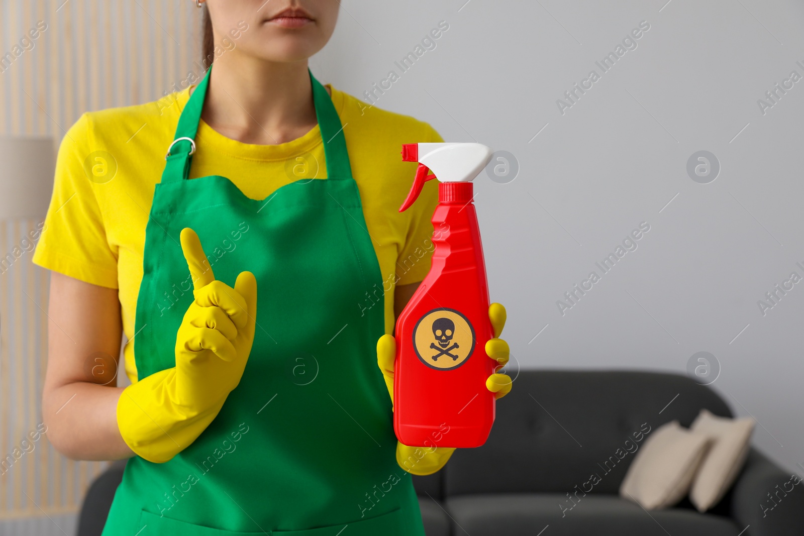 Photo of Woman showing bottle of toxic household chemical with warning sign, closeup