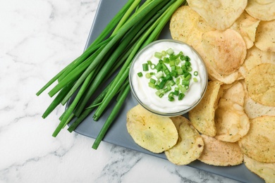 Photo of Sour cream and chips on white marble table, flat lay