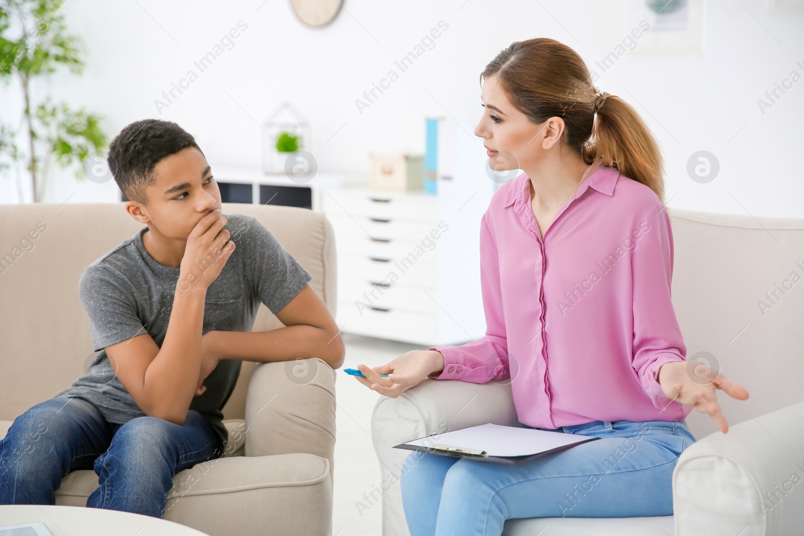 Photo of Female psychologist working with African American teenage boy in office