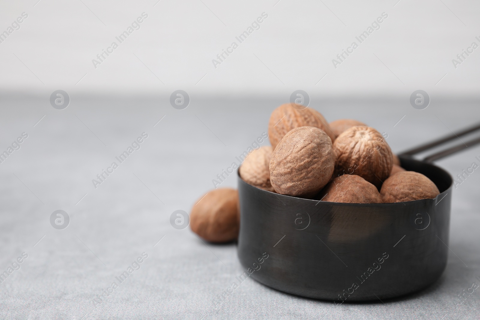 Photo of Whole nutmegs in small saucepan on light table. Space for text