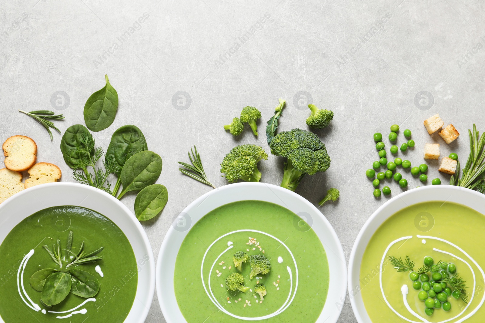 Photo of Dishes with different fresh vegetable detox soups made of green peas, broccoli, spinach and ingredients on table, flat lay