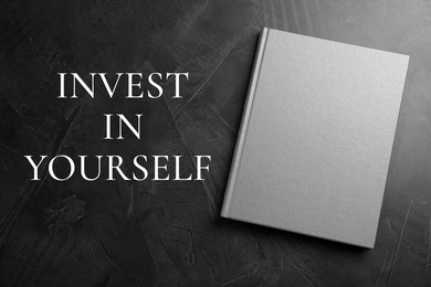 Image of Invest in yourself, affirmation. Book and words on black table, top view