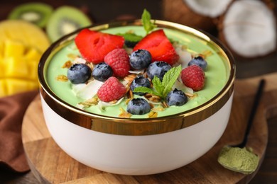 Photo of Tasty matcha smoothie bowl served with berries and oatmeal on table, closeup. Healthy breakfast