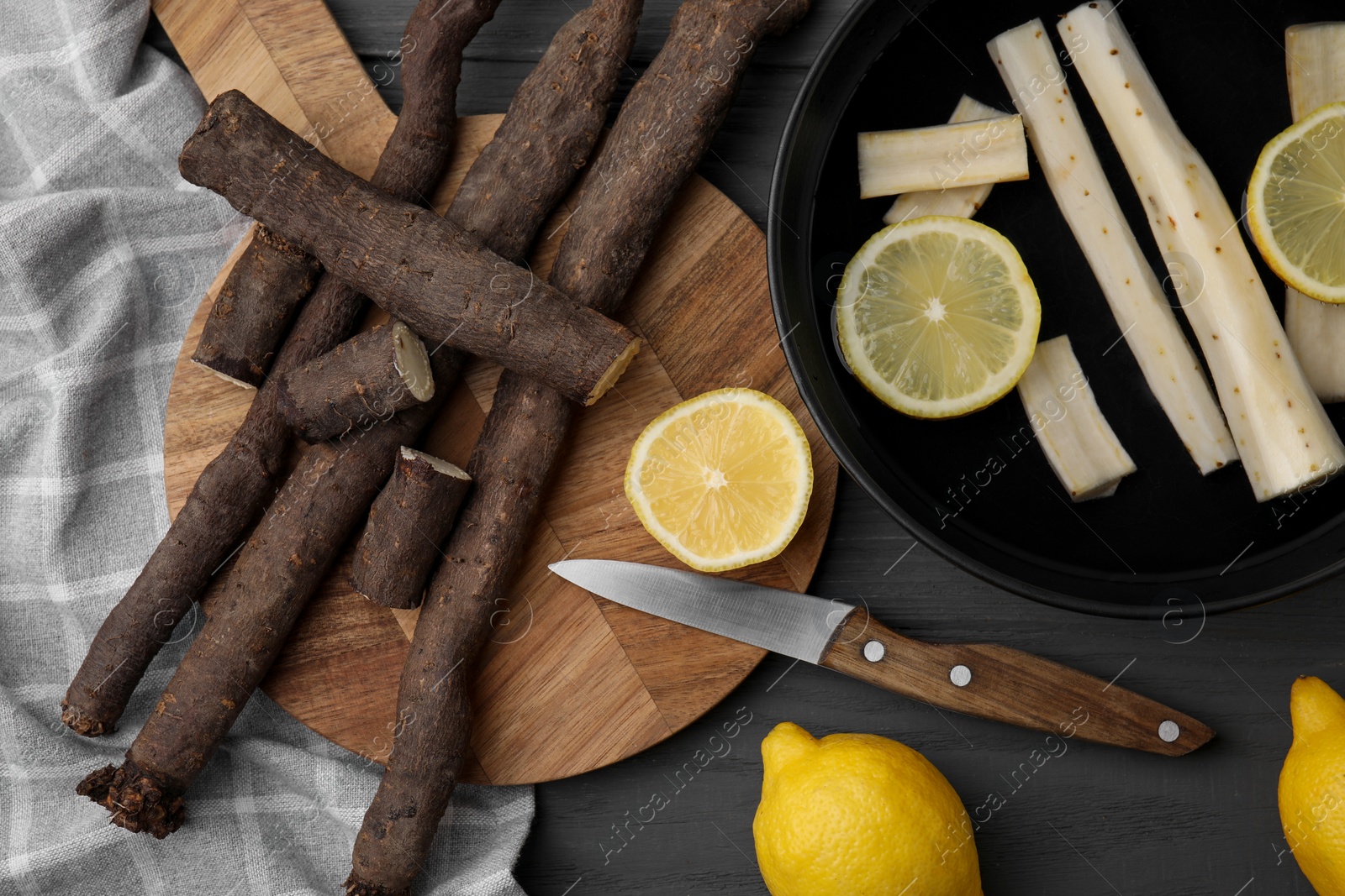 Photo of Raw salsify roots with lemon on grey wooden table, flat lay