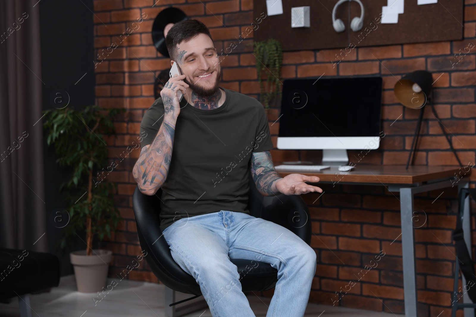 Photo of Smiling hipster man talking on smartphone in stylish room