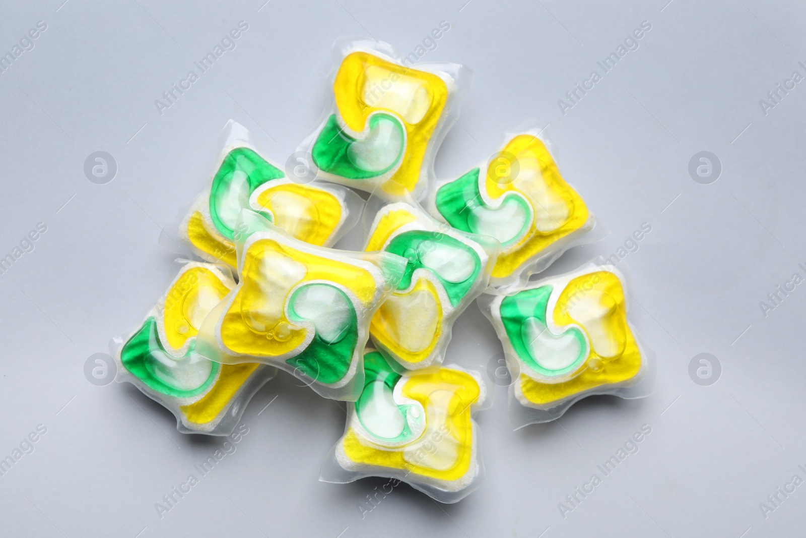 Photo of Many dishwasher detergent pods on light grey background, flat lay