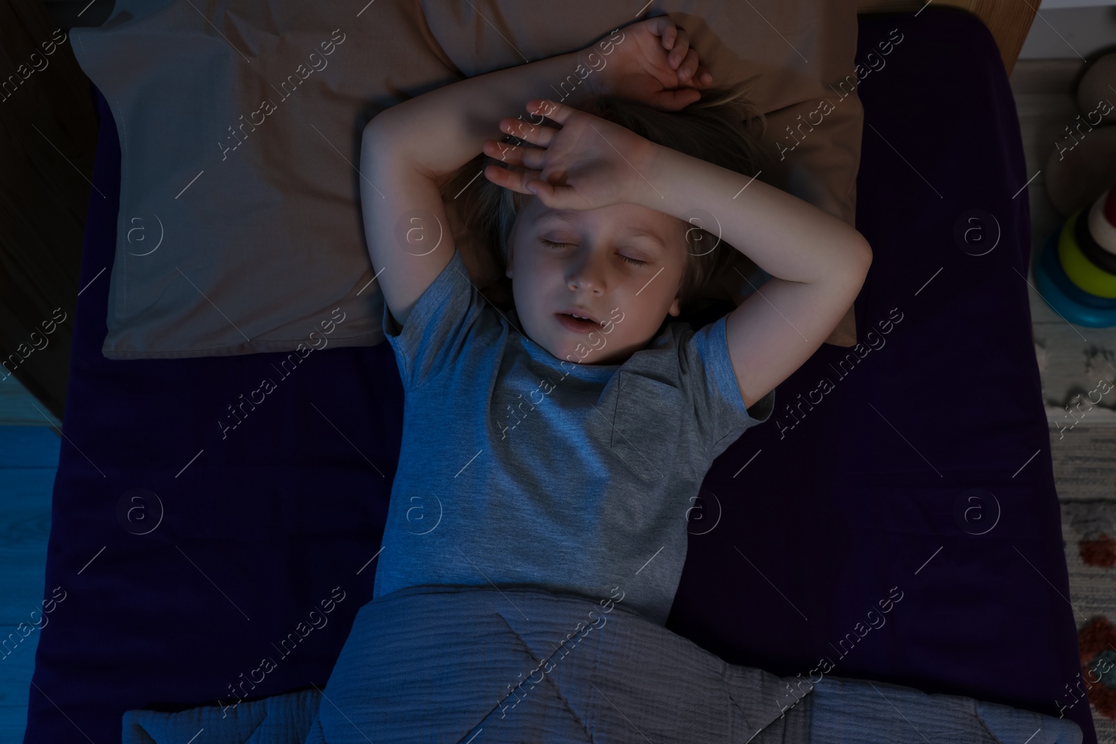 Photo of Little boy snoring while sleeping in bed at night, top view