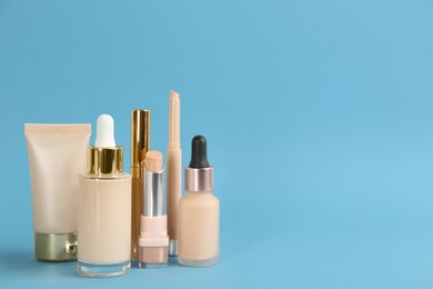 Photo of Foundation makeup products on light blue background, space for text. Decorative cosmetics