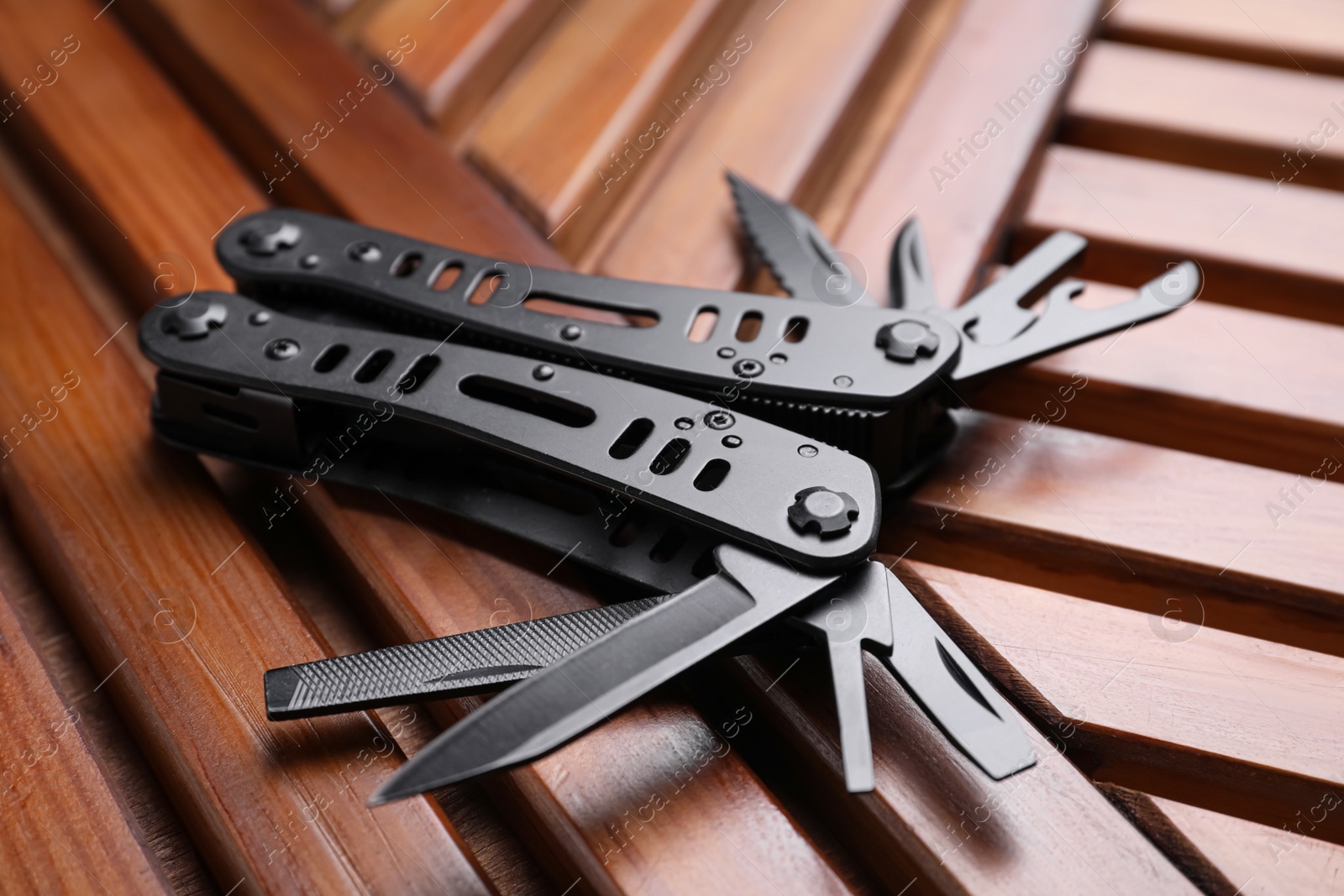 Photo of Modern compact portable multitool on wooden table, closeup