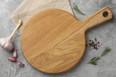 Photo of Cutting board, garlic, spices and rosemary on grey textured table, flat lay. Space for text