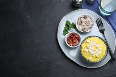 Photo of Traditional Ukrainian banosh served with brynza, pork cracklings and mushrooms on black table, flat lay. Space for text