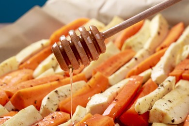 Pouring honey onto slices of parsnip and carrot, closeup