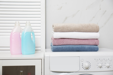 Photo of Stack of fresh towels and detergents in laundry room