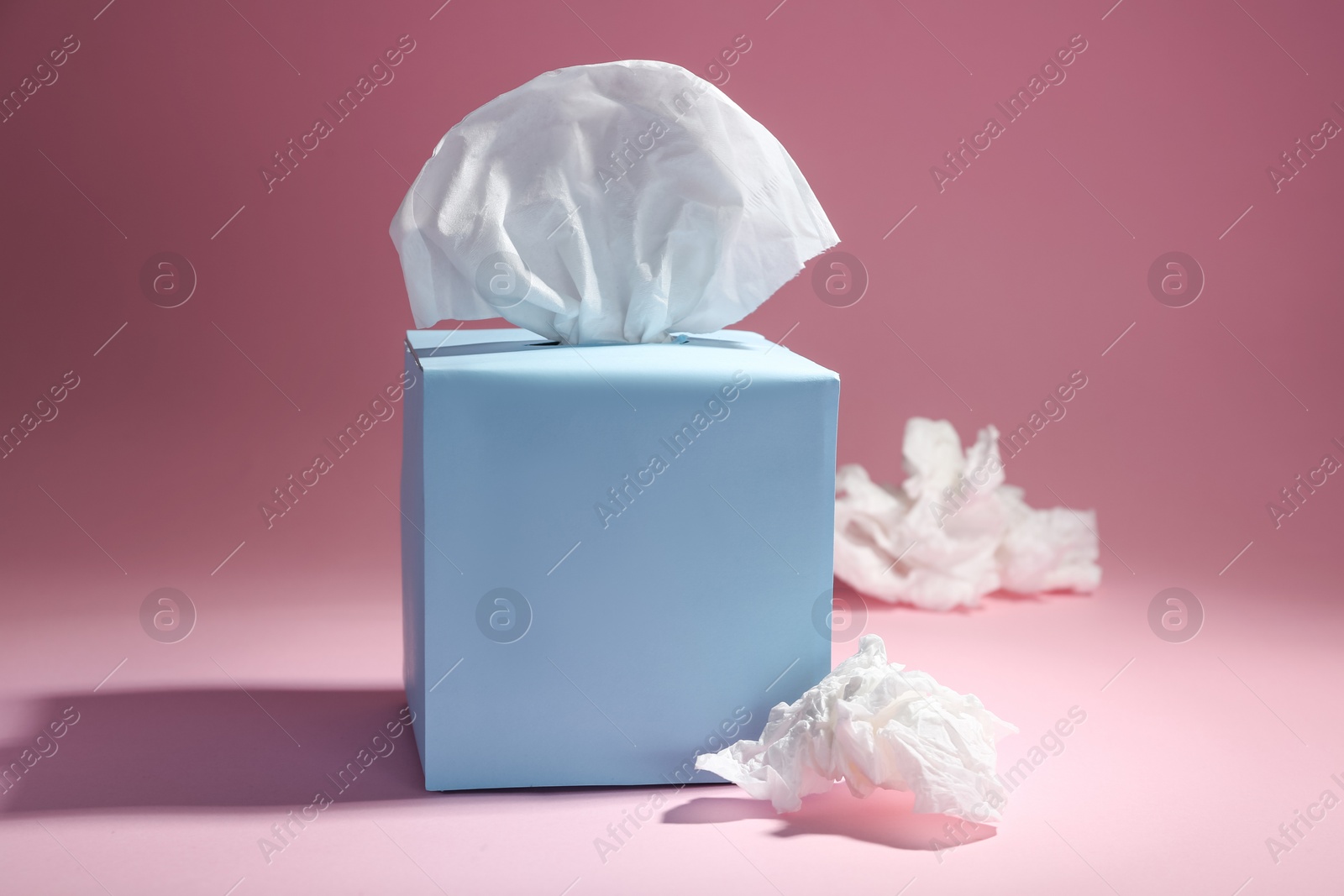 Photo of Box of paper tissues and used crumpled napkins on pink background