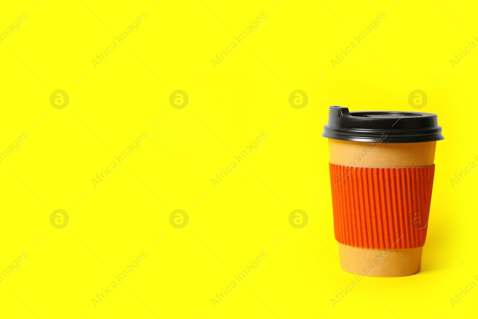 Photo of Takeaway paper coffee cup with cardboard sleeve on yellow background. Space for text