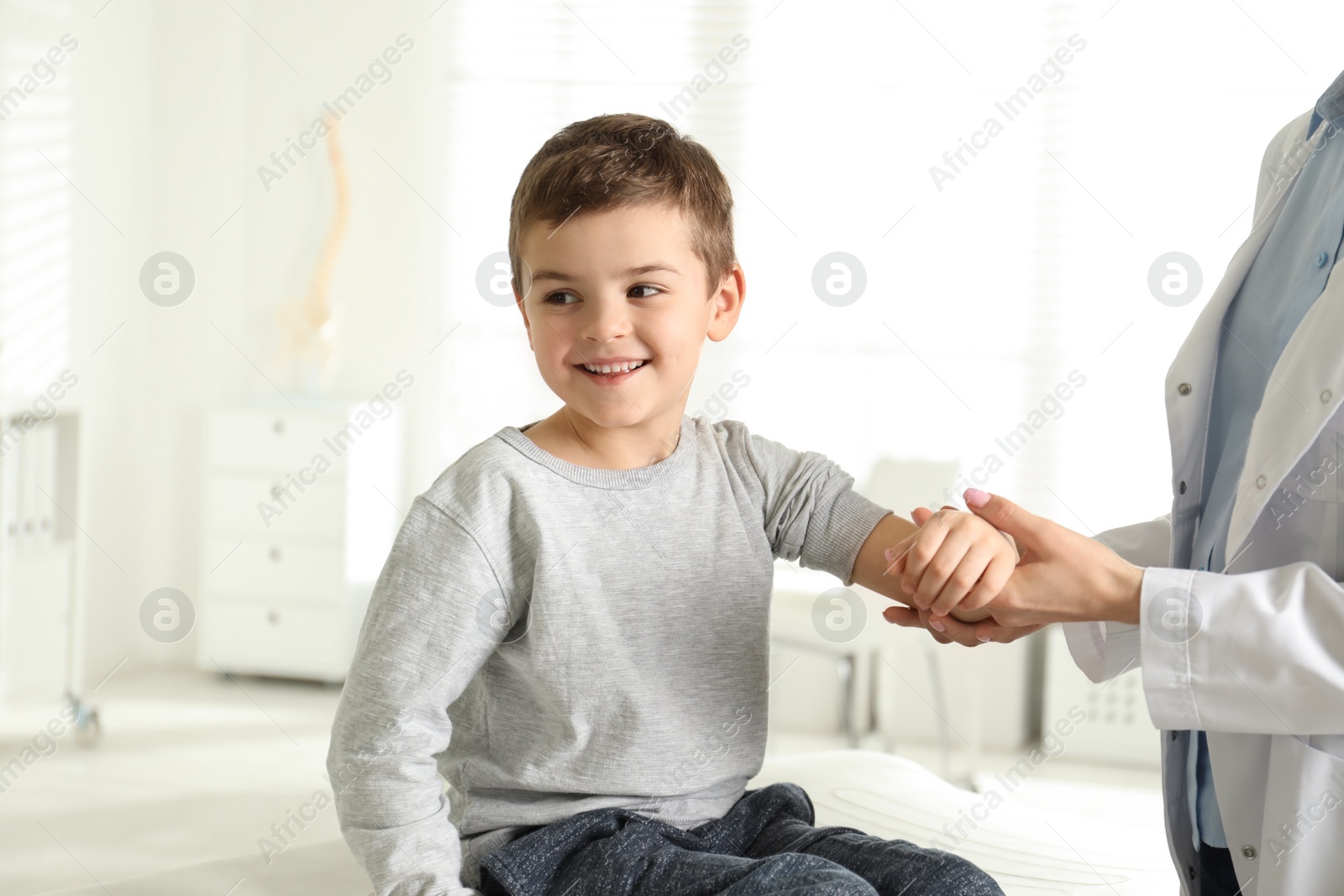 Photo of Professional orthopedist examining little patient's arm  in clinic